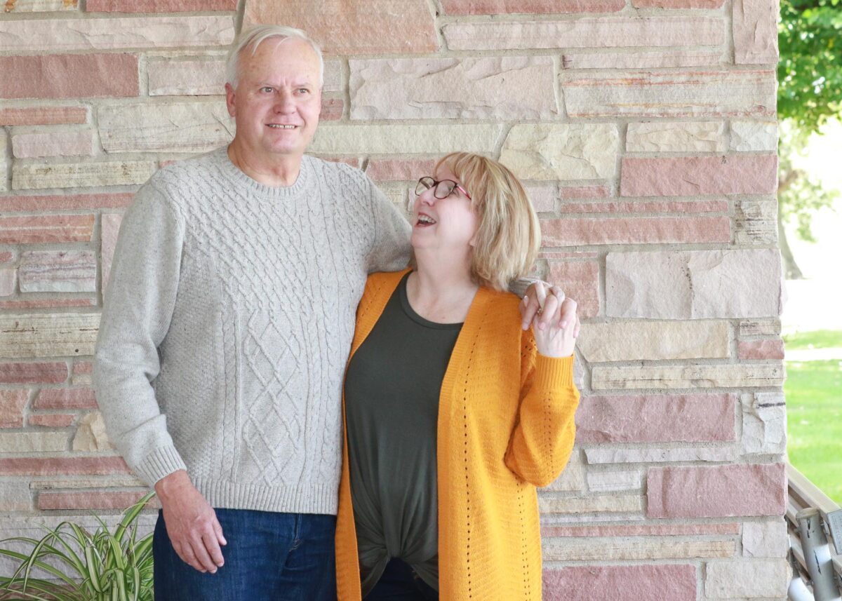 Sandy and Jesse Pape hold hands and laugh toward the camera.